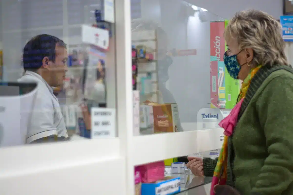 Pharmacien en blouse blanche discutant avec une cliente en officine