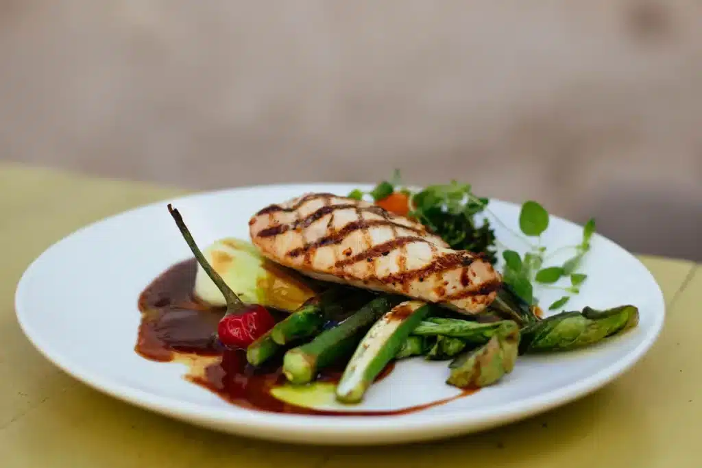 Assiette équilibrée avec protéines, légumes, céréales complètes et lipides sains sur une table de cuisine lumineuse.