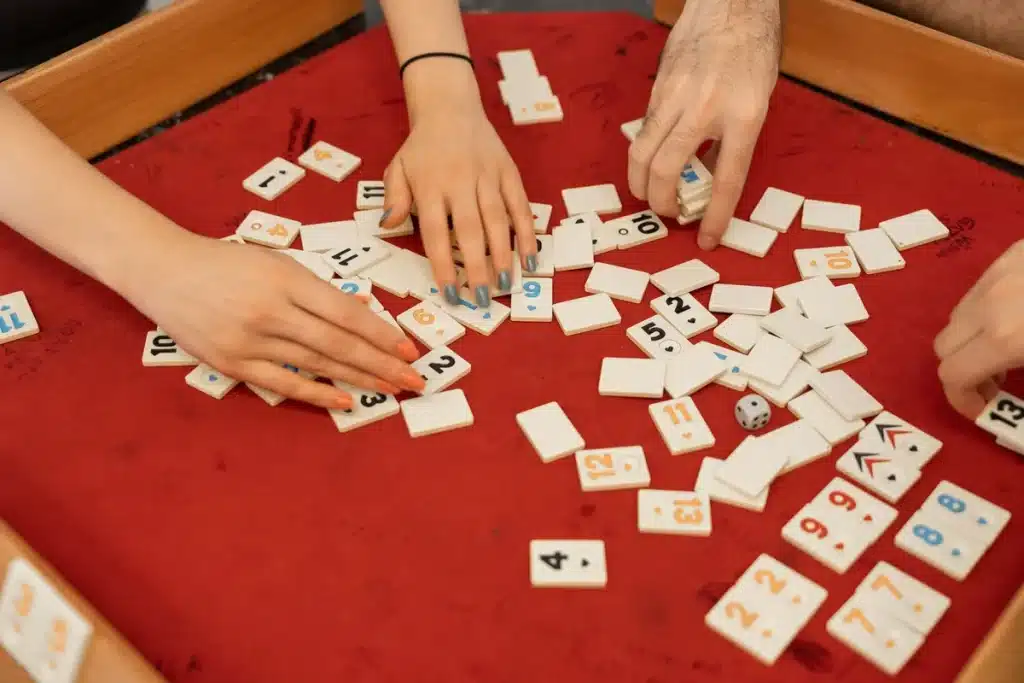 Mains arrangeant des tuiles de mahjong sur une surface avec symboles traditionnels visibles