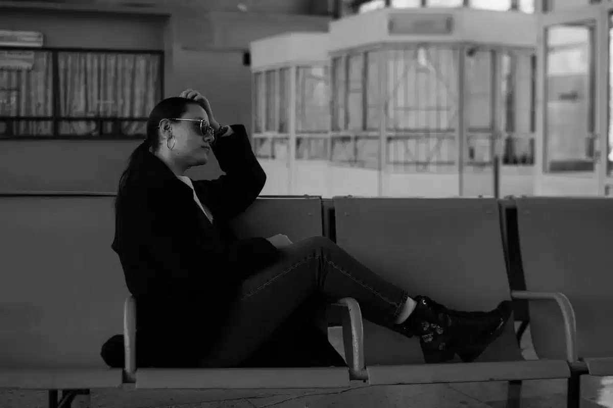 Personne assise se tenant la tête, yeux fermés, exprimant le malaise et le vertige
