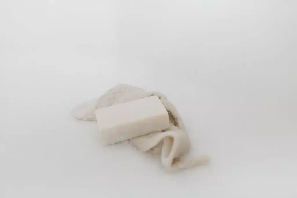 Mains savonnant un pain de savon artisanal sous l'eau courante avec mousse et bulles