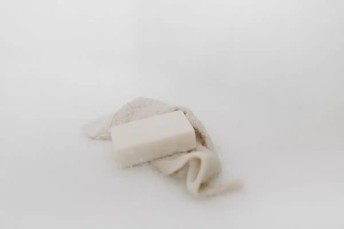 Mains savonnant un pain de savon artisanal sous l'eau courante avec mousse et bulles