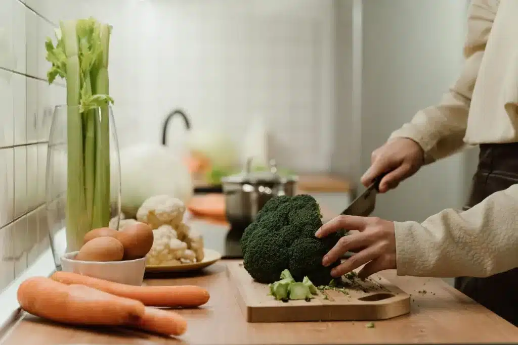 Mains d'une personne âgée arrangeant des légumes frais et des céréales complètes sur une assiette