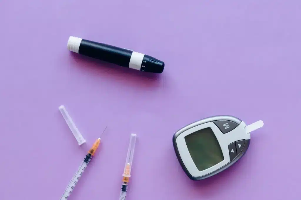 Vial de sang et glucomètre affichant des valeurs de glycémie sur un bureau de laboratoire