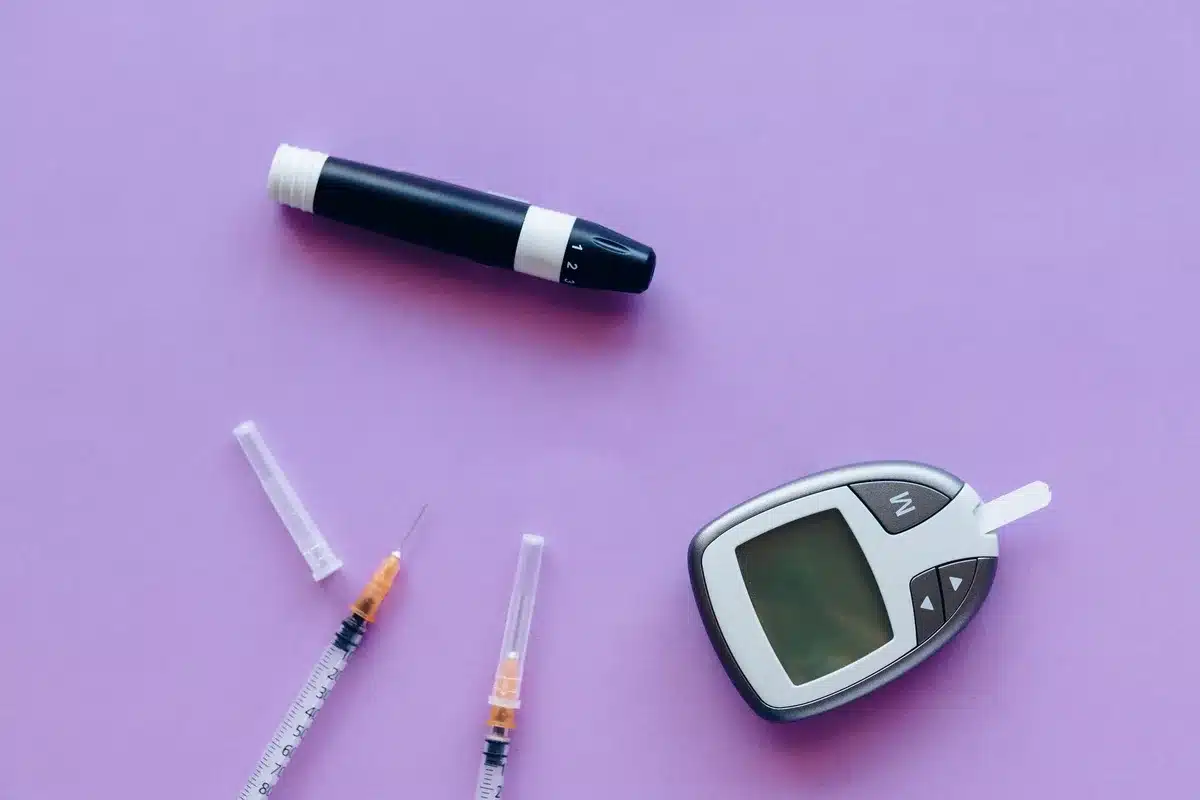 Vial de sang et glucomètre affichant des valeurs de glycémie sur un bureau de laboratoire