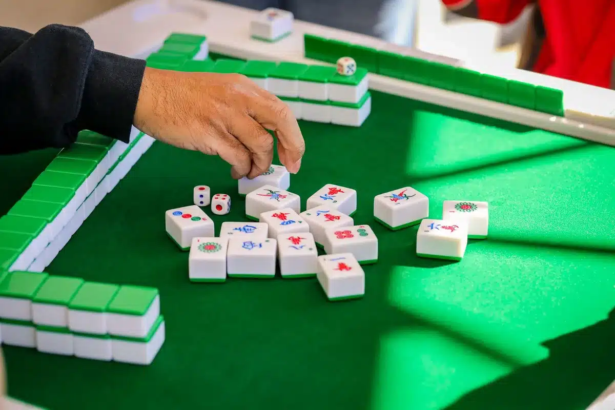 Main de joueur tenant des tuiles de mahjong lors d'une partie stratégique