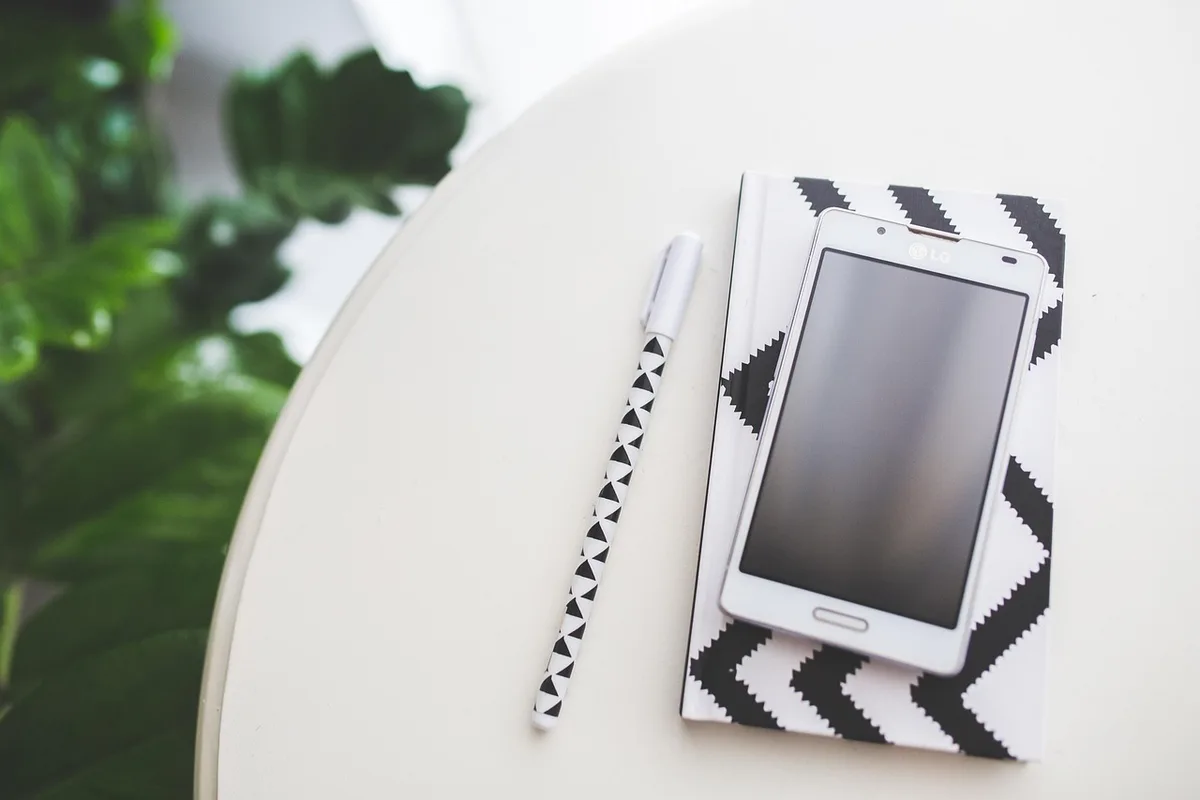 Personne calculant un bonus sur un carnet à côté d'un smartphone