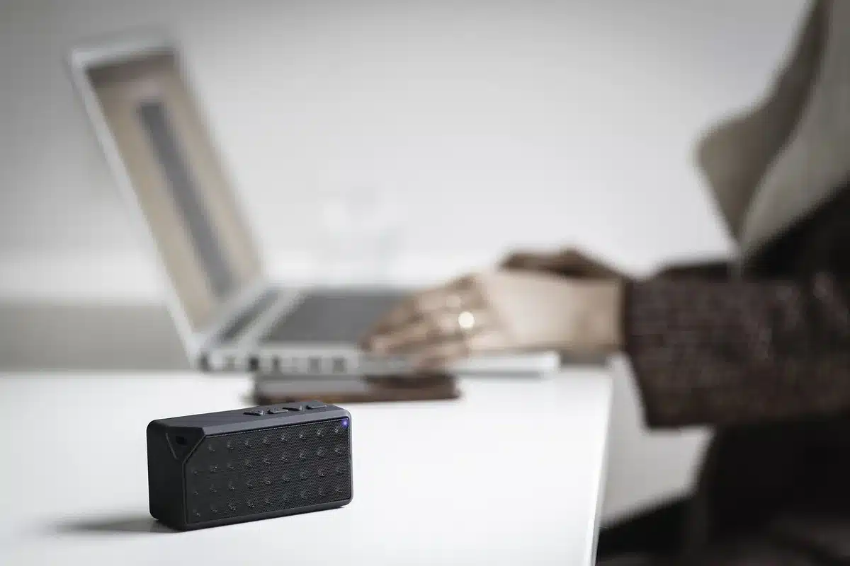 Aide auditive posée près d'un chargeur et d'un smartphone avec l'icône Bluetooth visible