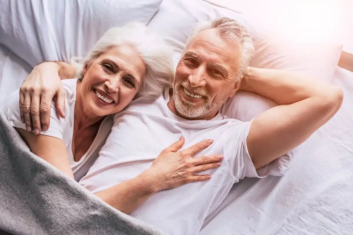 Aidant change la position d'un senior au lit pour prévenir les escarres