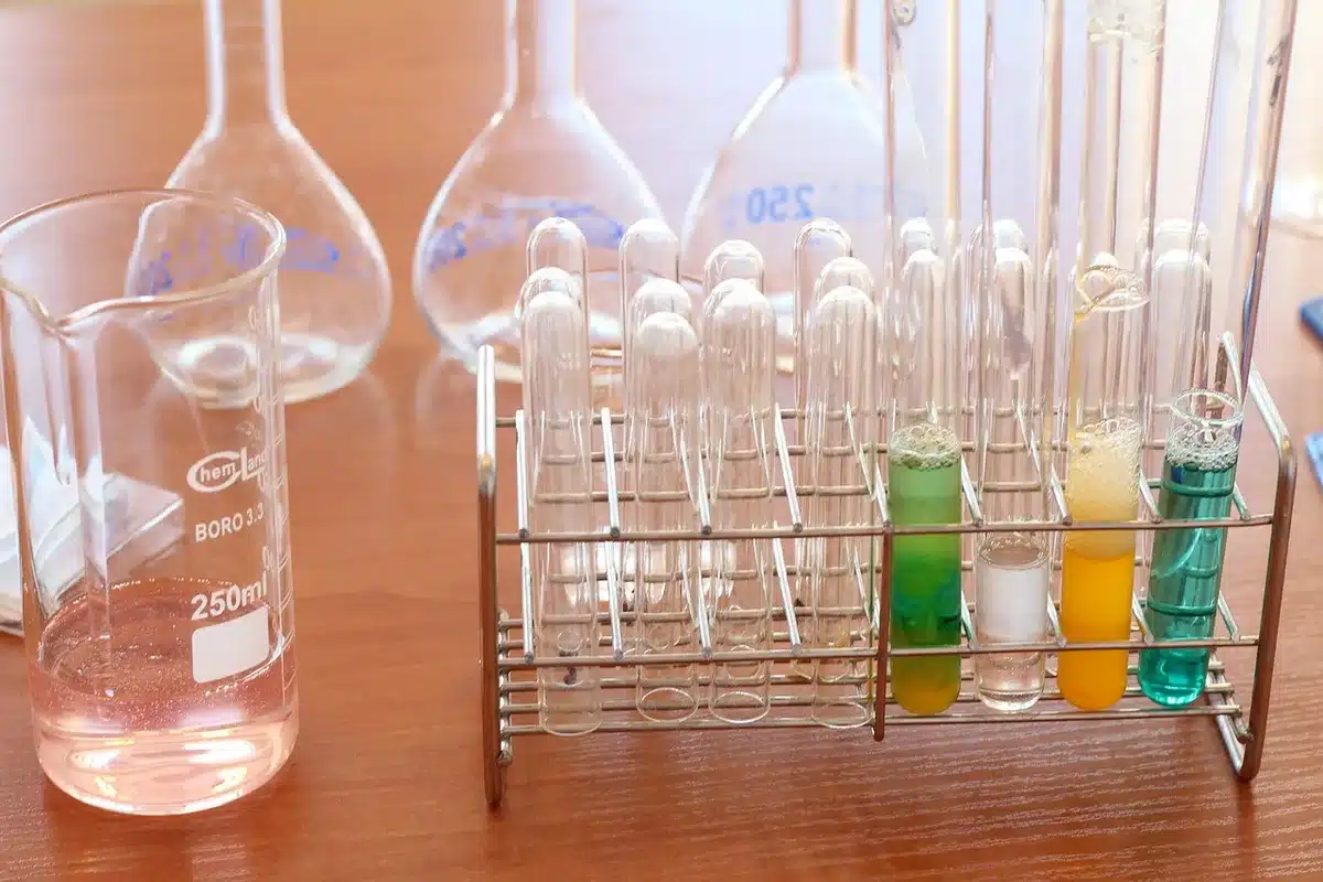 Tube de prélèvement tenu au-dessus d'une table d'examen, résultats de laboratoire flous en fond