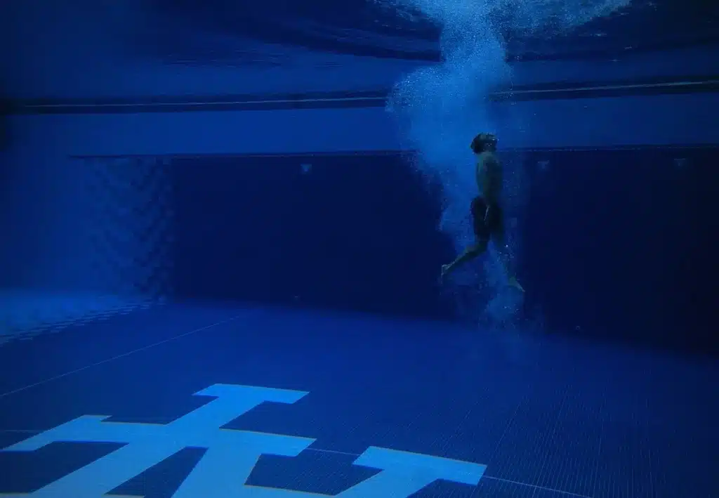 Femme âgée effectuant un exercice doux en piscine, immergée partiellement dans l'eau calme