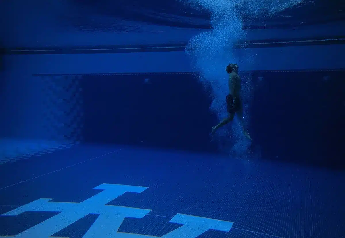 Femme âgée effectuant un exercice doux en piscine, immergée partiellement dans l'eau calme