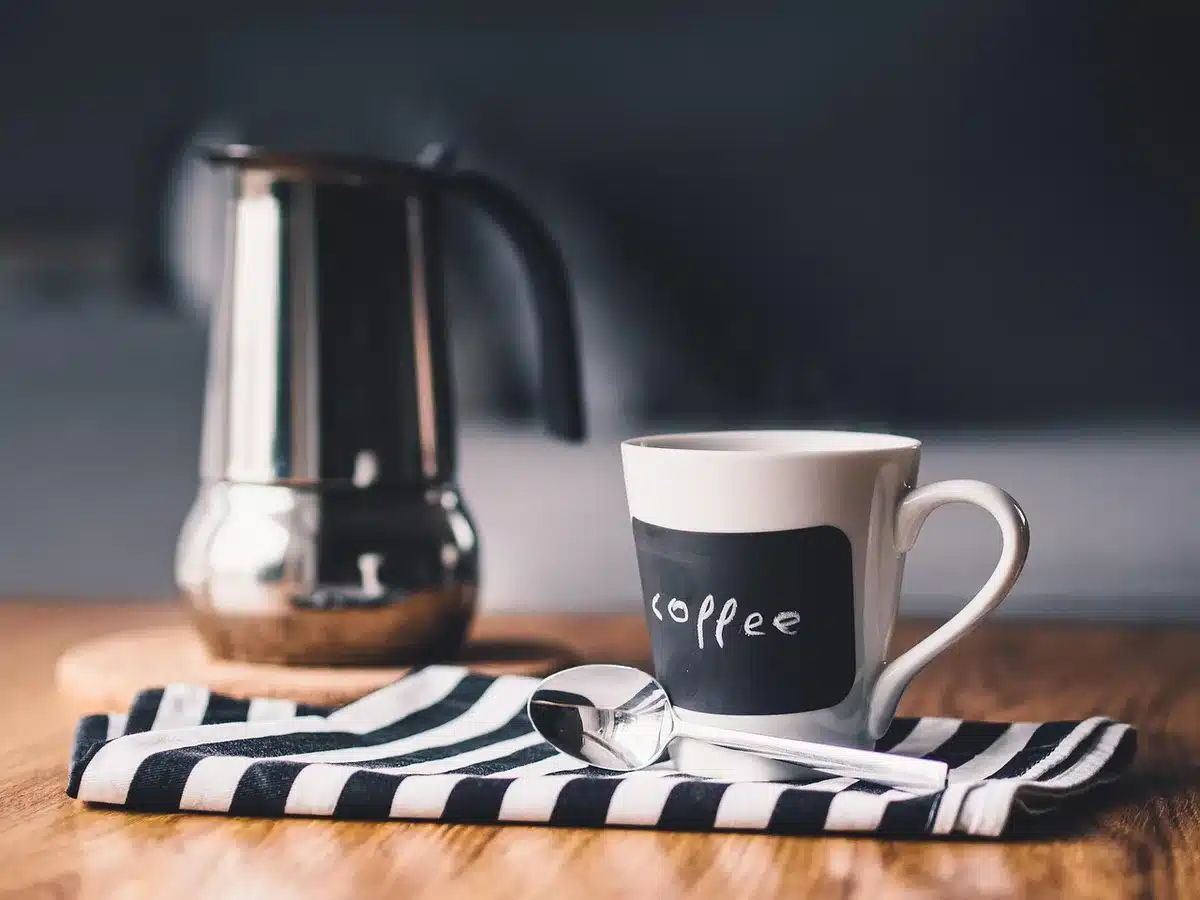 Tasse de café émulsionnée avec un mousseur sur une table claire