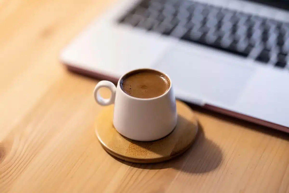 Tasse à café réutilisable, serviette et carnet posés sur un banc de musculation baigné de lumière