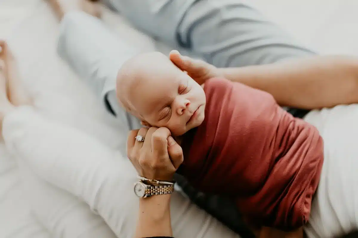 Main d'un parent massant doucement la gencive d'un bébé près d'un anneau de dentition