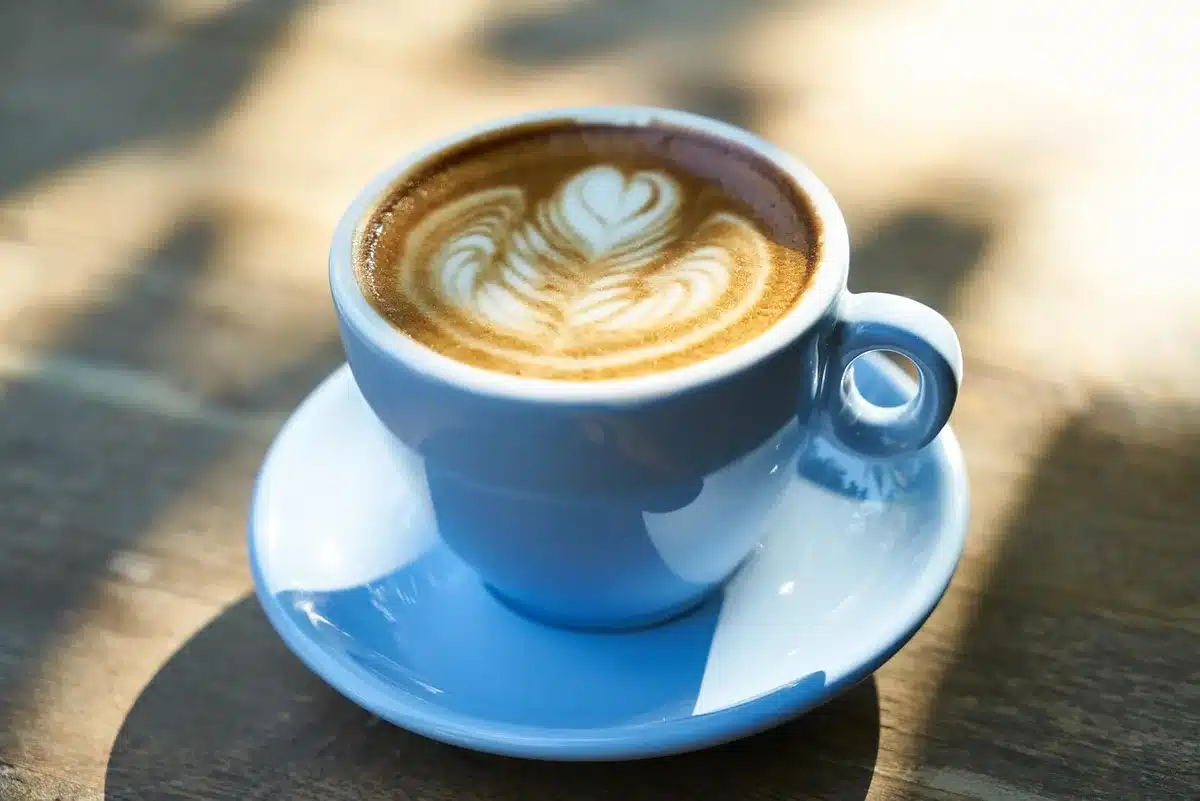 Préparation d'un vanilla latte avec espresso et mousse de lait, sirop ajouté dans la tasse