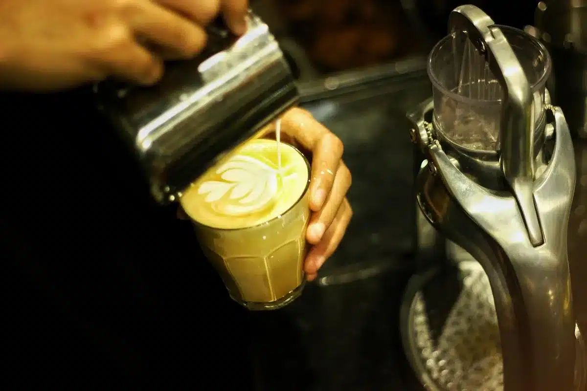 Lait chauffé et mousse légère dans un pichet près d'une tasse